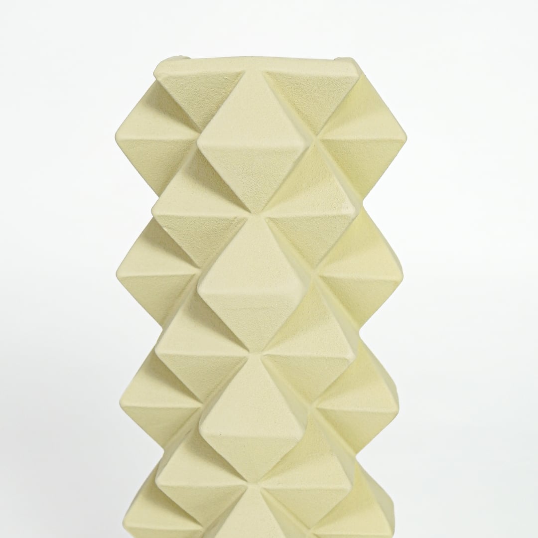 Close view of yellow ceramic vase showcasing detailed geometric pattern and smooth matte finish.