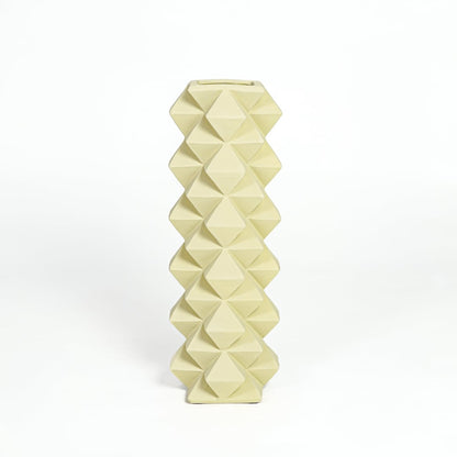 Contemporary yellow ceramic flower vase with sculpted diamond design isolated on white background.
