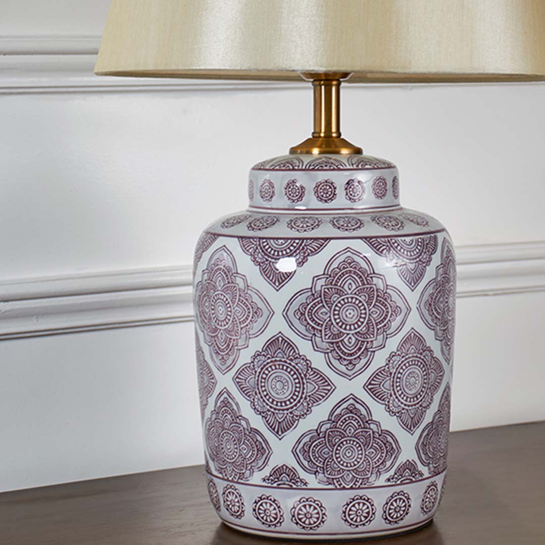 Closeup view of white ceramic lamp base with intricate printed pattern and gold detailing for home lighting decor.