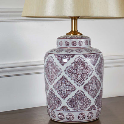 Closeup view of white ceramic lamp base with intricate printed pattern and gold detailing for home lighting decor.
