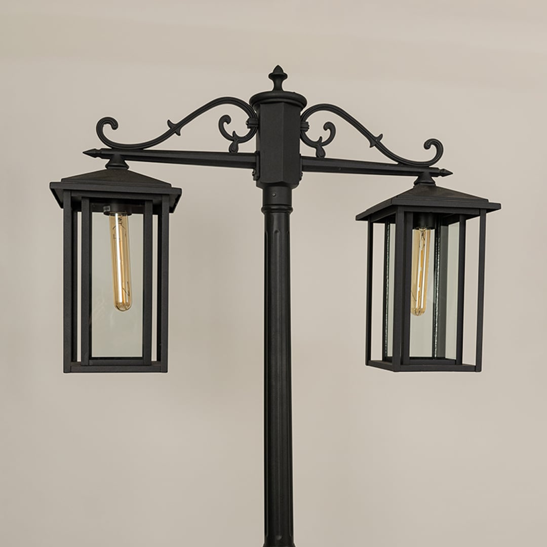 Closeup of black metal lantern head showing clear glass panels and warm light glow perfect for outdoor driveway garden and pathway Decor.