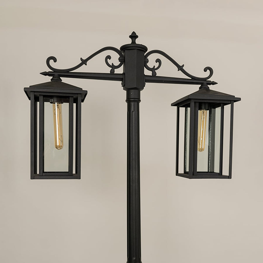 Closeup of black metal lantern head showing clear glass panels and warm light glow perfect for outdoor driveway garden and pathway Decor.