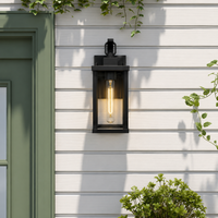 Modern black metal rectangular clear glass wall lantern on white horizontal siding for contemporary home patio entryway.