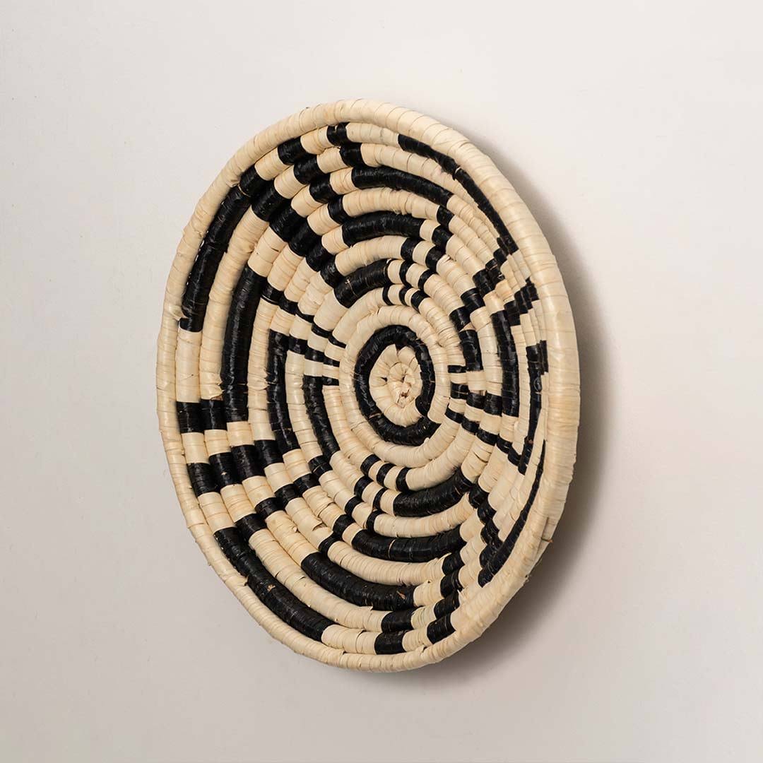 Side view of handcrafted black cream woven seagrass wall basket with abstract spiral zigzag pattern for bohemian home wall decor.