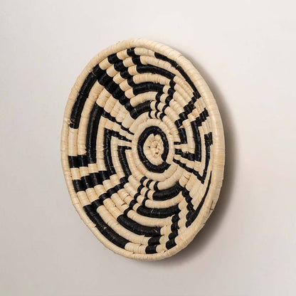 Side view of handcrafted black cream woven seagrass wall basket with abstract spiral zigzag pattern for bohemian home wall decor.