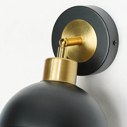 Closeup of black metal wall light with gold holder showcasing smooth finish and premium detailing for modern decor styling.