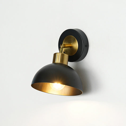 Black metal wall light with dome shade and gold holder emitting warm glow ideal for modern bedroom or hallway wall decor.