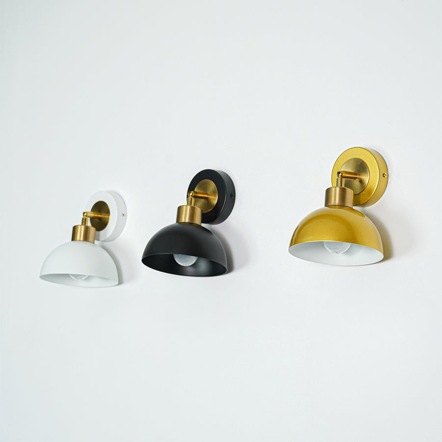 Set of wall lights with white black and gold dome shades perfect for modern bedroom or hallway wall decor placement.