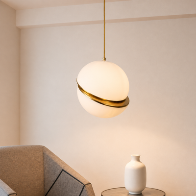 A modern spherical pendant light with a frosted white globe shade and a polished gold metallic band, hanging in a minimalist room setting.
