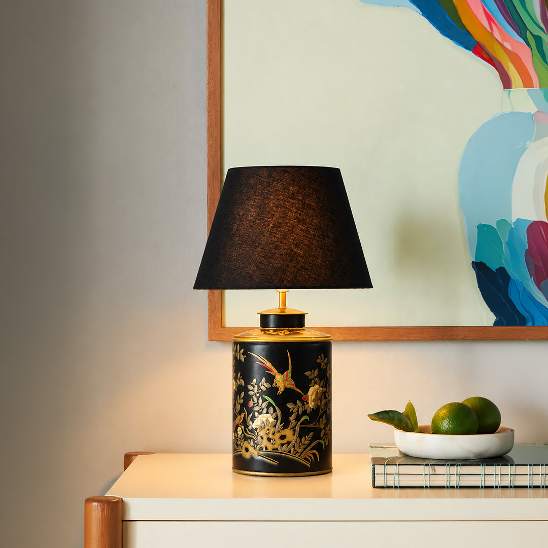 Black floral ceramic table lamp with black fabric shade adding sophisticated ambient lighting to modern console styling.