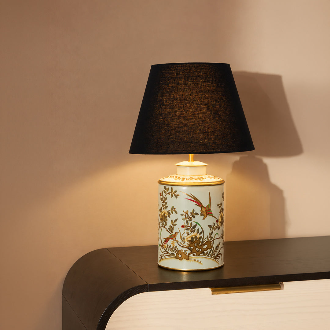 Floral ceramic table lamp with black fabric shade casting warm ambient light for elegant bedside and accent table decor.