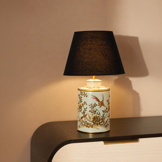 Floral ceramic table lamp with black fabric shade casting warm ambient light for elegant bedside and accent table decor.
