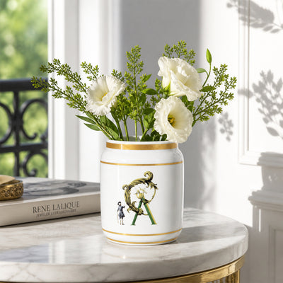 White ceramic flower jar with gold detailing placed on marble table for elegant modern home decor.