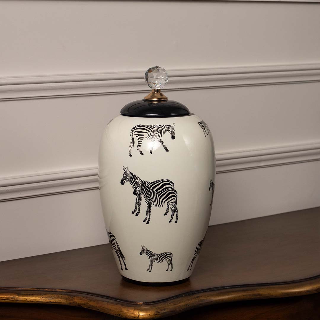 Closeup of white ceramic jar showing detailed black zebra artwork and glossy finish with elegant crystal knob top.