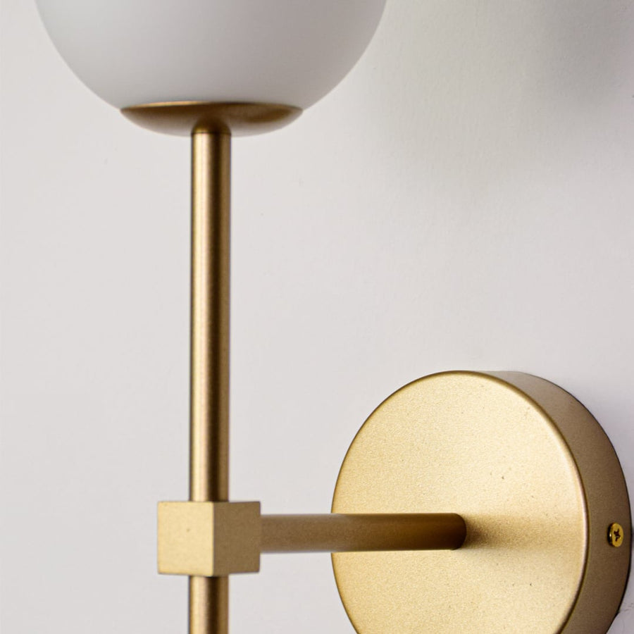 Closeup of Nordic golden wall lamp with glass ball shade showing polished metal finish soft glow and modern indoor wall lighting appeal.