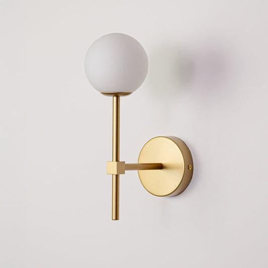 Gold metal wall light with white glass globe switched off on white background highlighting sleek modern wall mounted design.