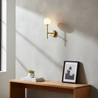 Gold metal wall light with white glass globe styled on modern interior wall creating soft ambient lighting for elegant home decor.