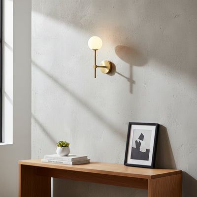 Gold metal wall light with white glass globe styled on modern interior wall creating soft ambient lighting for elegant home decor.