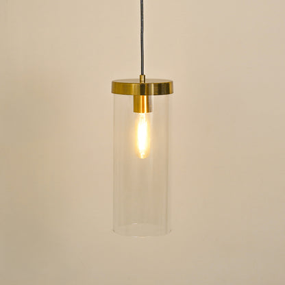 Clear glass tube pendant light with brushed brass accents illuminated for elegant ceiling decor.