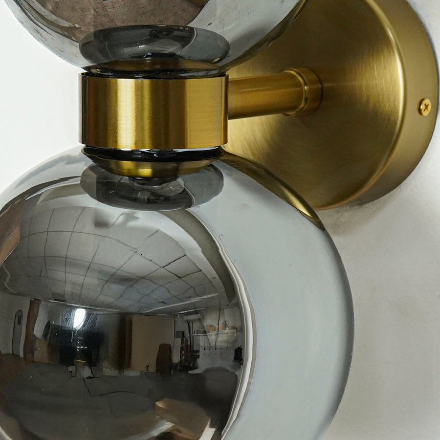 Close view of smoked glass globe wall light with gold mount modern decorative wall lamp for bedroom living room lighting.