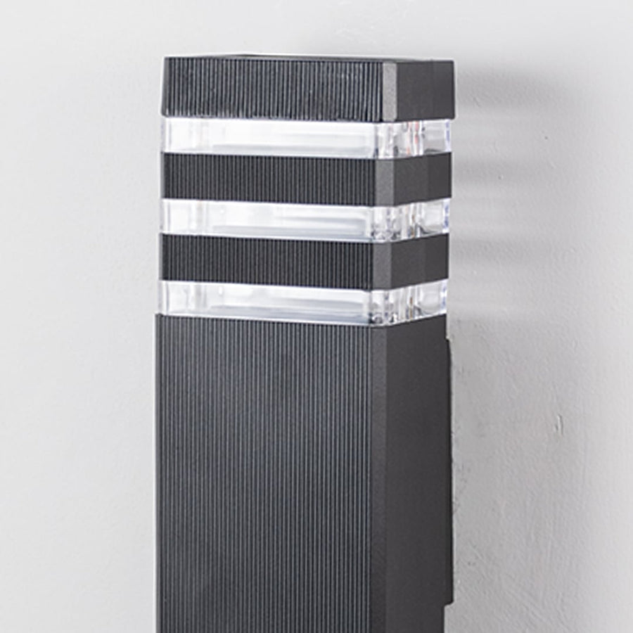 Closeup of tall black wall light showing precise detailing and clear acrylic light diffusers.