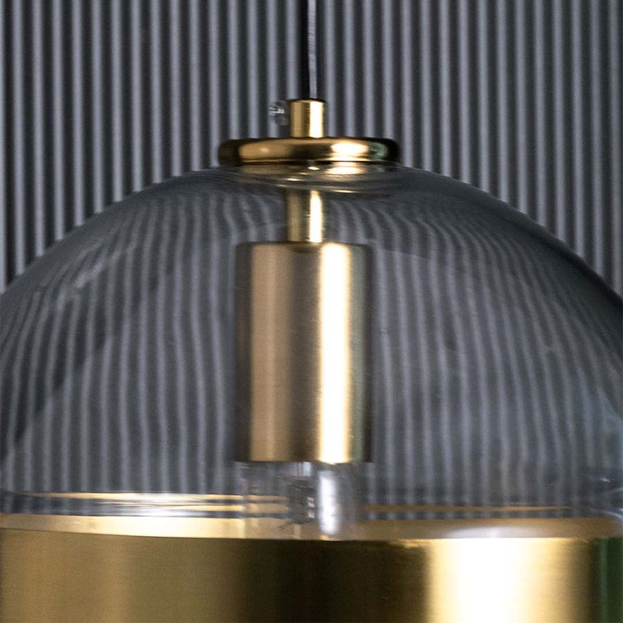 Detailed closeup of a modern glass pendant showing the gold road and clear spherical form with visible bulb elements creating a refined contemporary look.