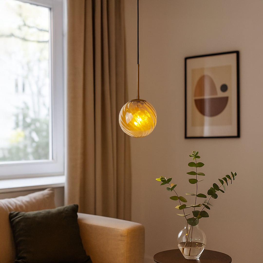 A modern gold and amber glass pendant light glowing warmly in a cozy living room creating soft ambient lighting ideal for sofas corners and reading spaces.