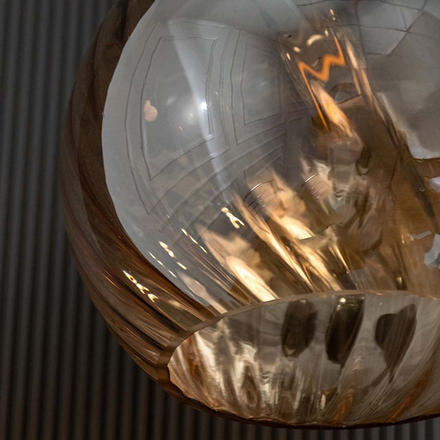 Close-up of amber glass pendant light with warm glowing bulb