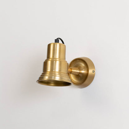 Gold metal wall mounted light turned off on white background highlighting minimal form and premium metallic finish.