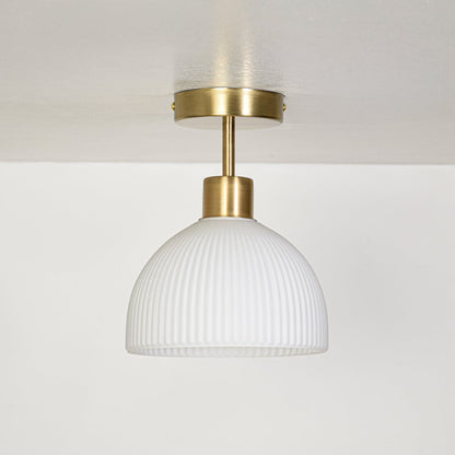 Minimal ceiling pendant light with ribbed white glass shade and gold metal canopy displayed on off white background.