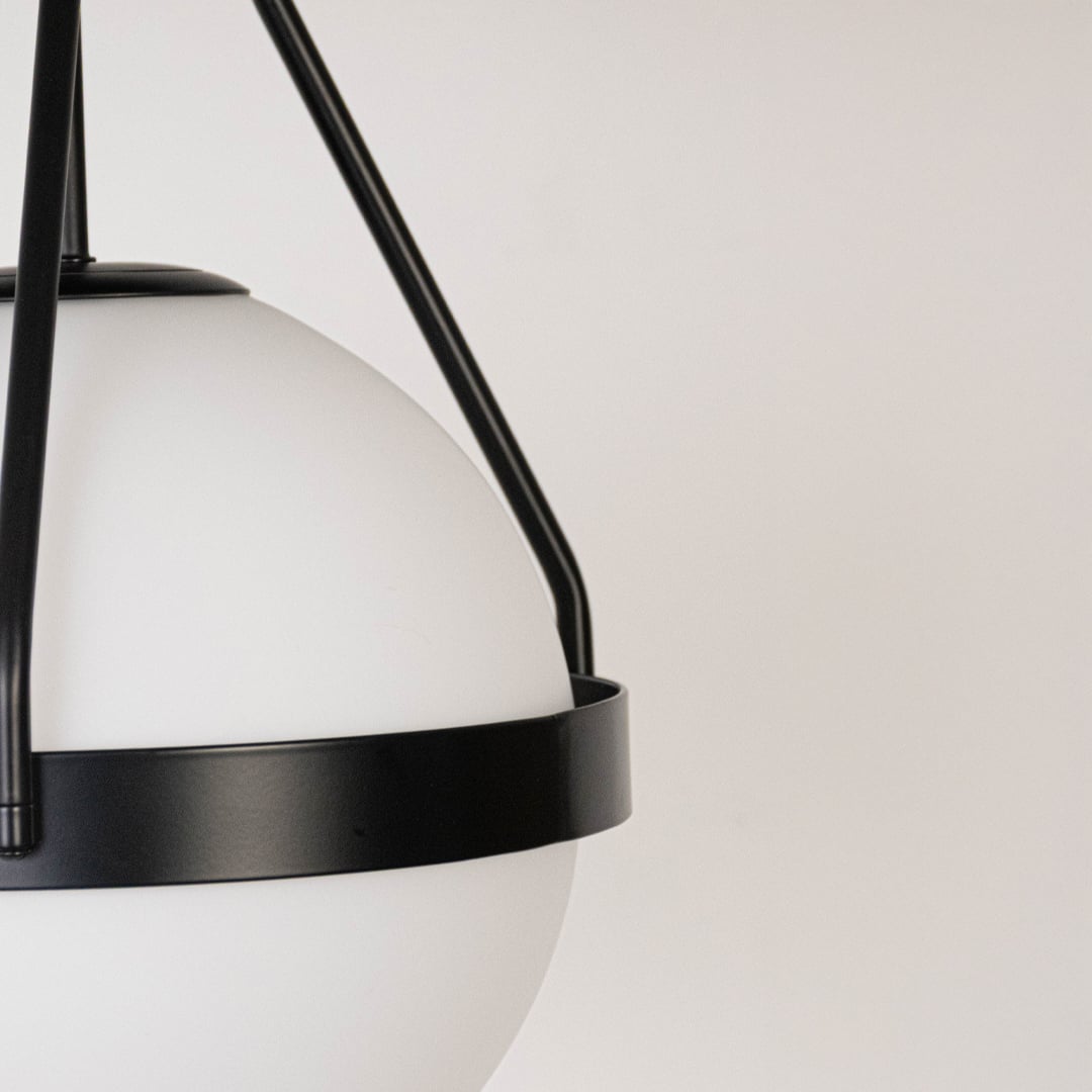 Closeup of black ceiling light with frosted glass globe shade and sleek frame for elegant modern ceiling lighting decor.
