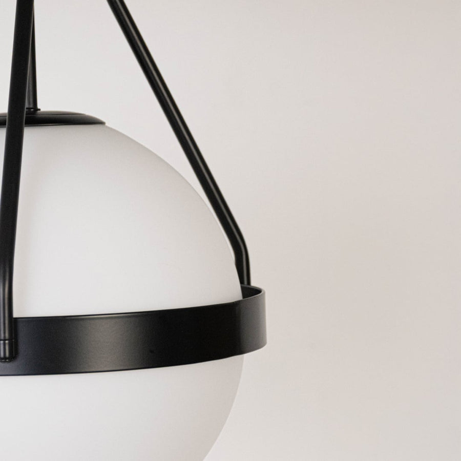Closeup of black ceiling light with frosted glass globe shade and sleek frame for elegant modern ceiling lighting decor.