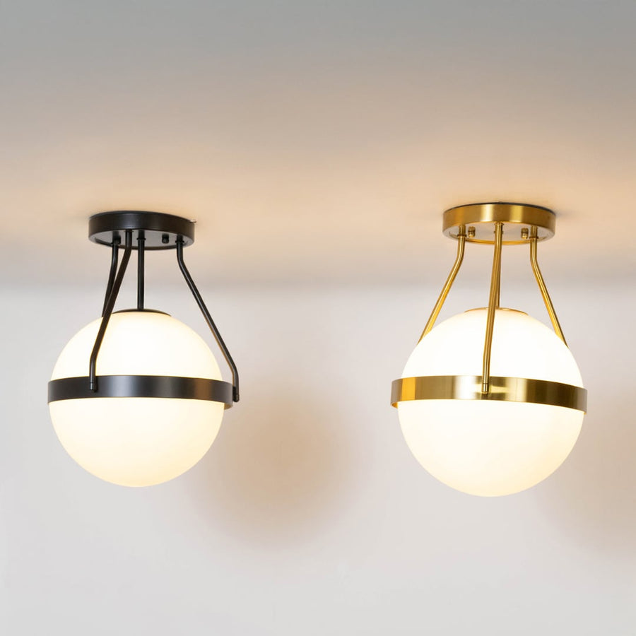 Black and gold ceiling lights with frosted glass globes glowing on white background for modern home interior lighting.