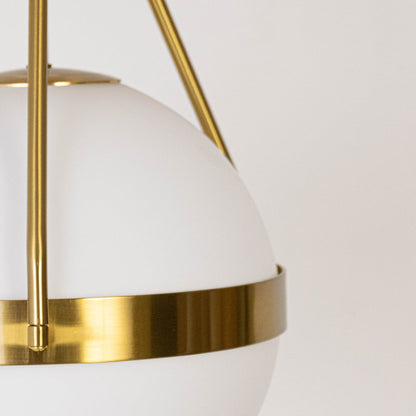 Closeup of modern ceiling light with gold finish and frosted glass globe shade for elegant interior home lighting design.