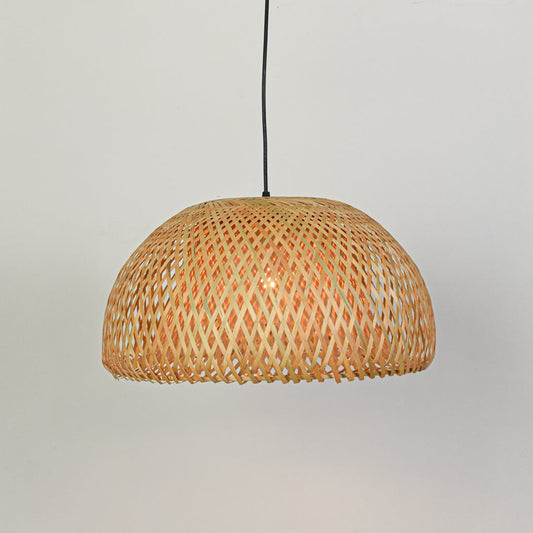 Natural rattan pendant ceiling light switched on against white background casting warm patterned illumination.