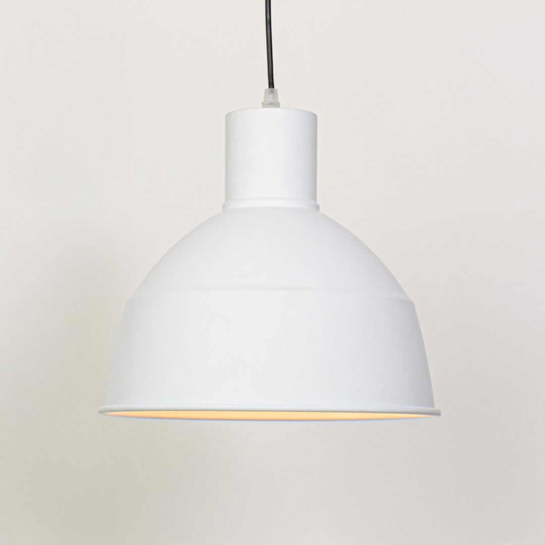 White metal pendant ceiling light switched on against white background producing soft focused downward illumination.