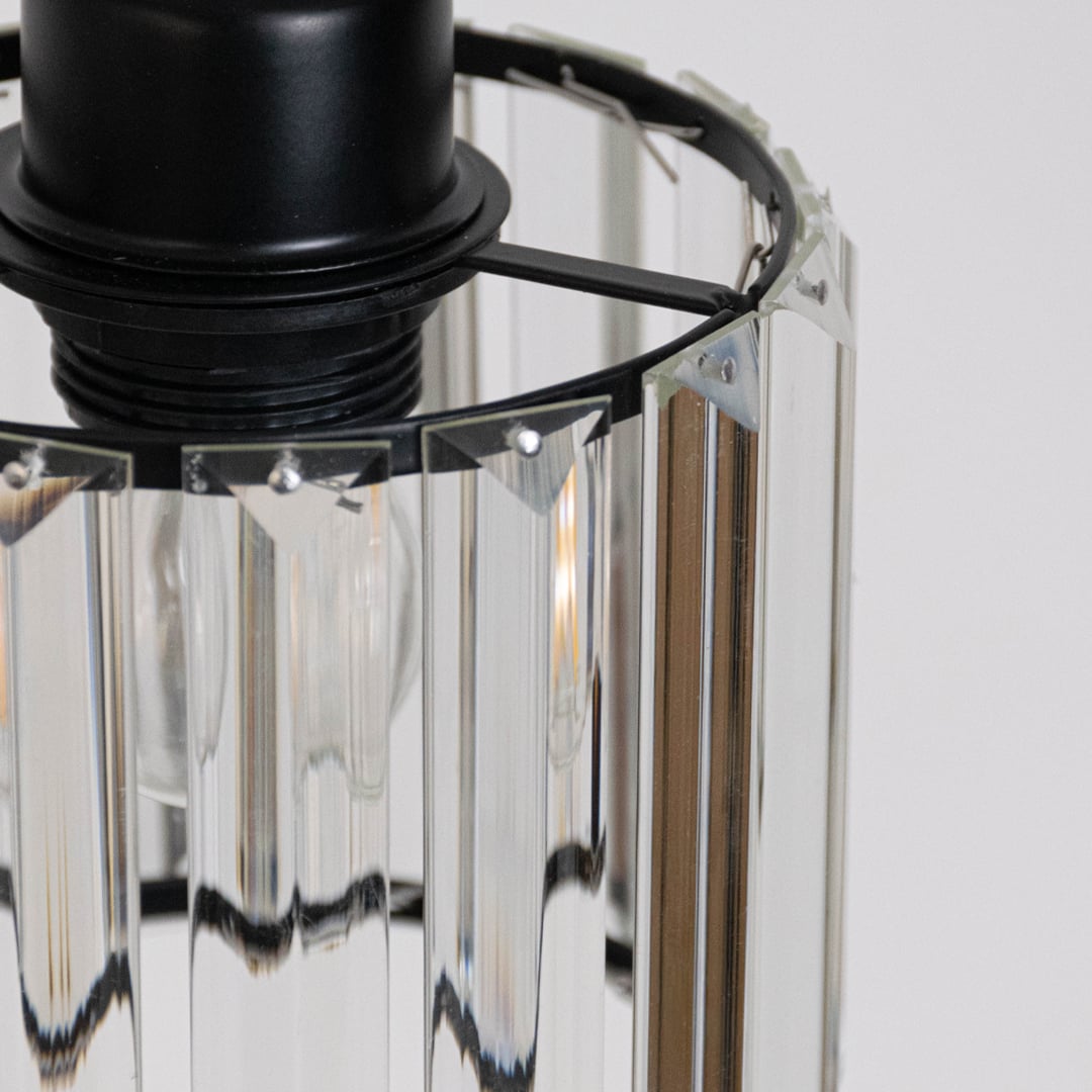 Closeup of glass pendant light with ribbed glass shade and black metal fixture for modern interiors.