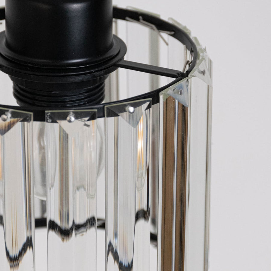 Closeup of glass pendant light with ribbed glass shade and black metal fixture for modern interiors.