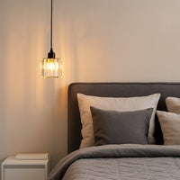 Clear ribbed glass pendant light with black finish illuminating bedside space with modern elegance.