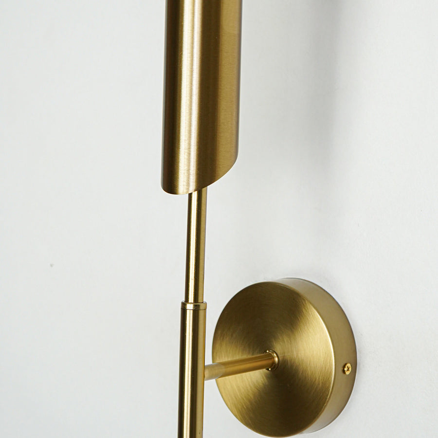 Closeup of gold metal wall light with cylindrical design showcasing smooth finish and premium detailing for modern interior decor.