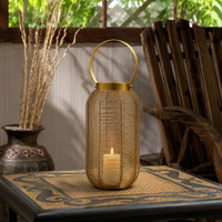Boho gold woven wire mesh floor lantern with a large circular loop handle sitting on an ornate patterned side table for rustic porch decor.