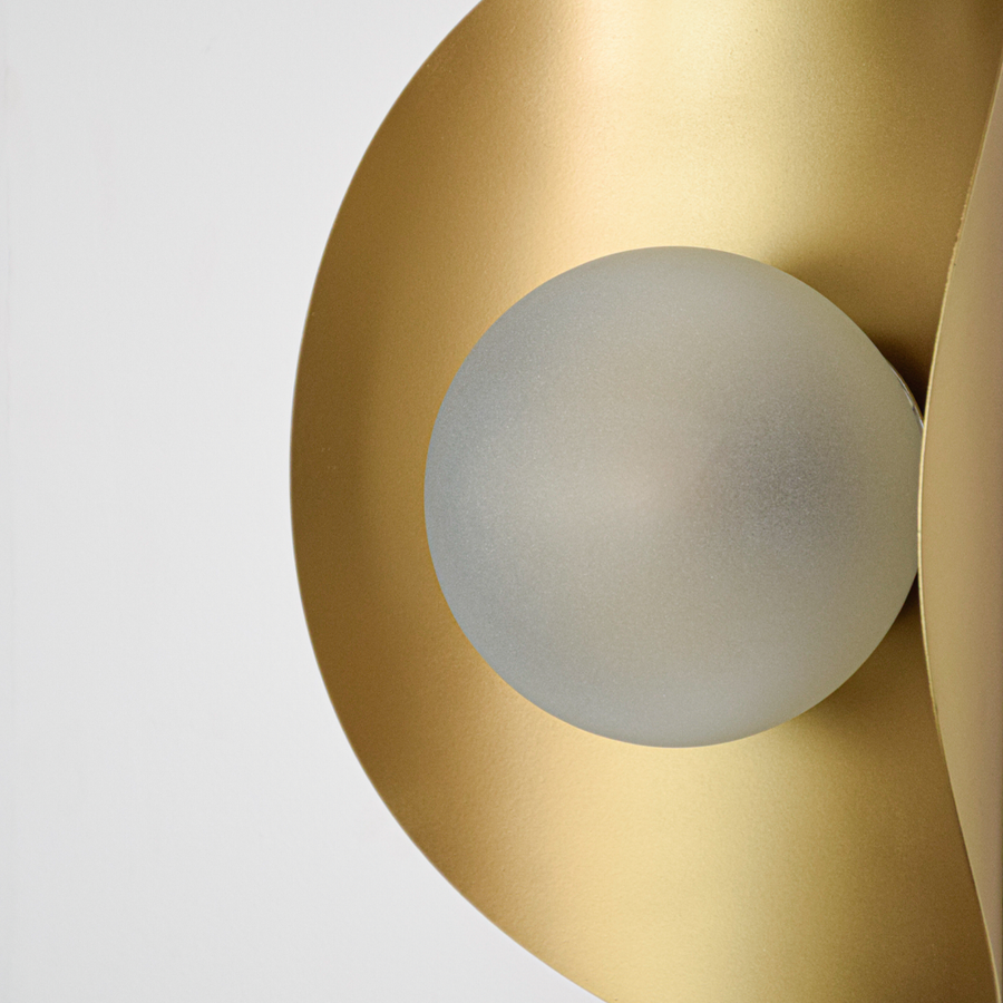 Wall light closeup highlighting smooth gold metal curves with soft frosted glass center showcasing refined craftsmanship and elegant architectural design.