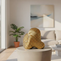 Gold metal abstract decor sculpture with textured swirl design styled on console table for luxury living room accent.
