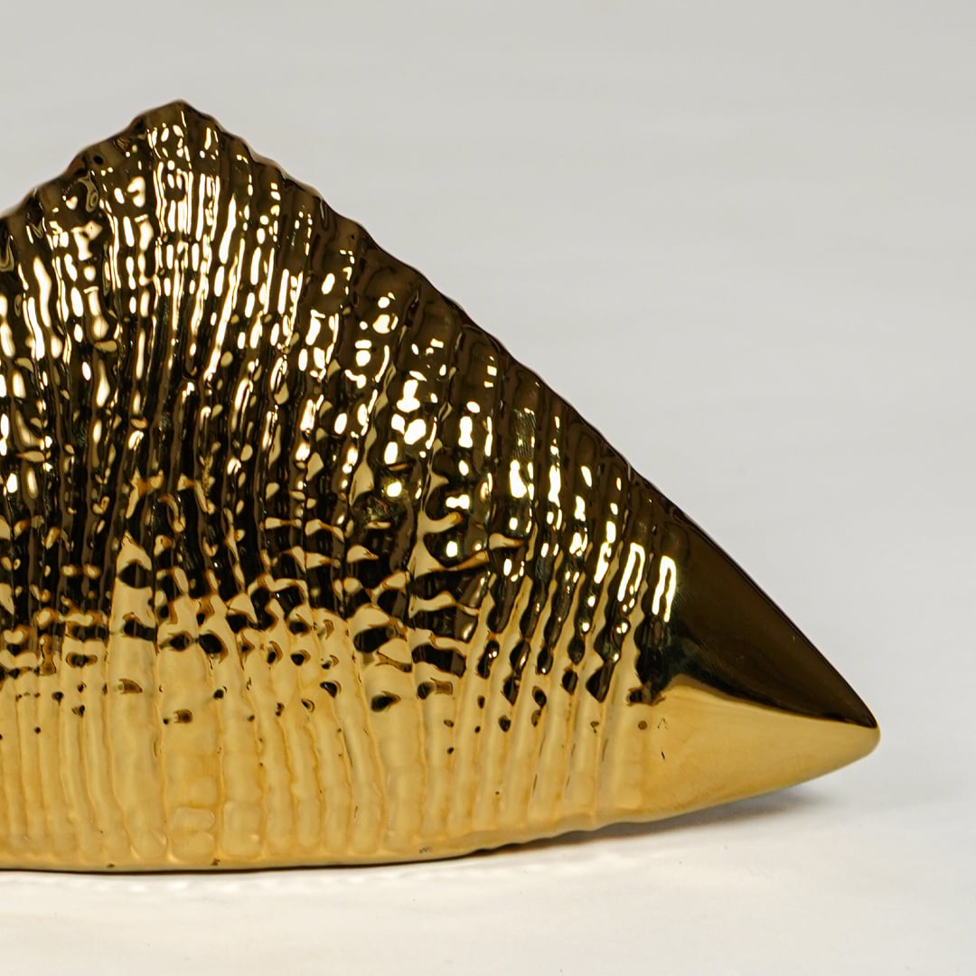Close view of gold striped ceramic triangle decor featuring glossy metallic finish and ribbed pattern.