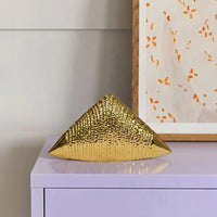 Gold metal pyramid decor accent placed on console table for luxury modern home decor styling ideas.