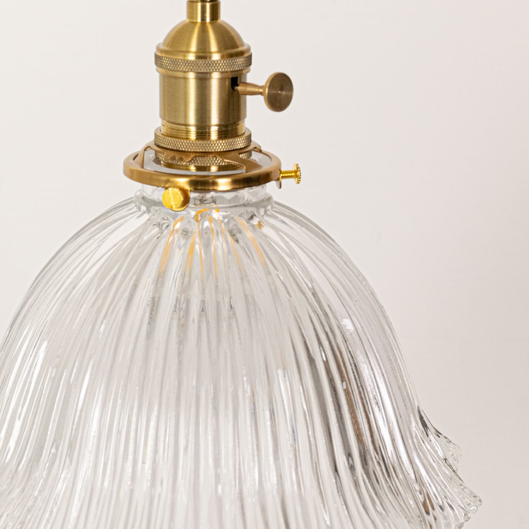 Closeup of sculpted clear glass and brass metal pendant light highlighting refined craftsmanship.