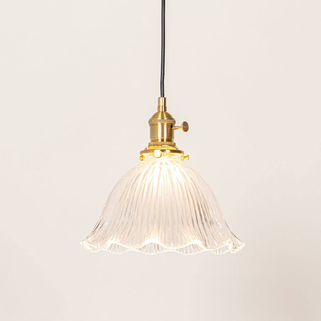 Fluted clear glass and brass metal pendant light designed for stylish dining room decor spaces.