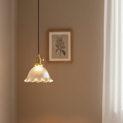 Ribbed clear glass and brass metal pendant light creating cozy ambience in modern interiors.