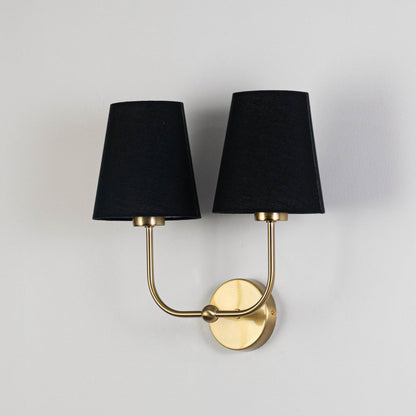 Gold double wall sconce with black fabric shades shown on a white background for clear product detailing.