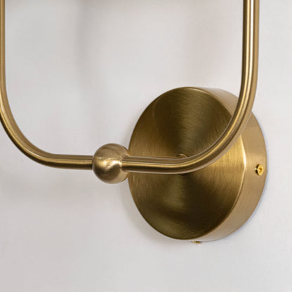 Closeup of gold metal double wall sconce with white fabric shades highlighting smooth finish and elegant design.